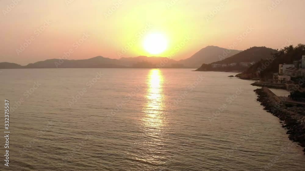 Slow forward rising shot above water with hazy mountains in distance in front of beautiful sunset at golden hour Slow forward rising shot above water with hazy mountains in distance in front of beautiful sunset at golden hour