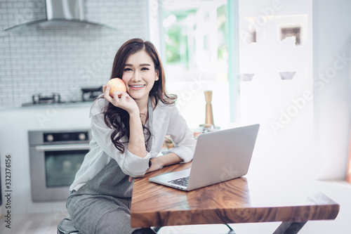 Portrait of beautiful young latin woman talking over the phone while cooking in kitchen