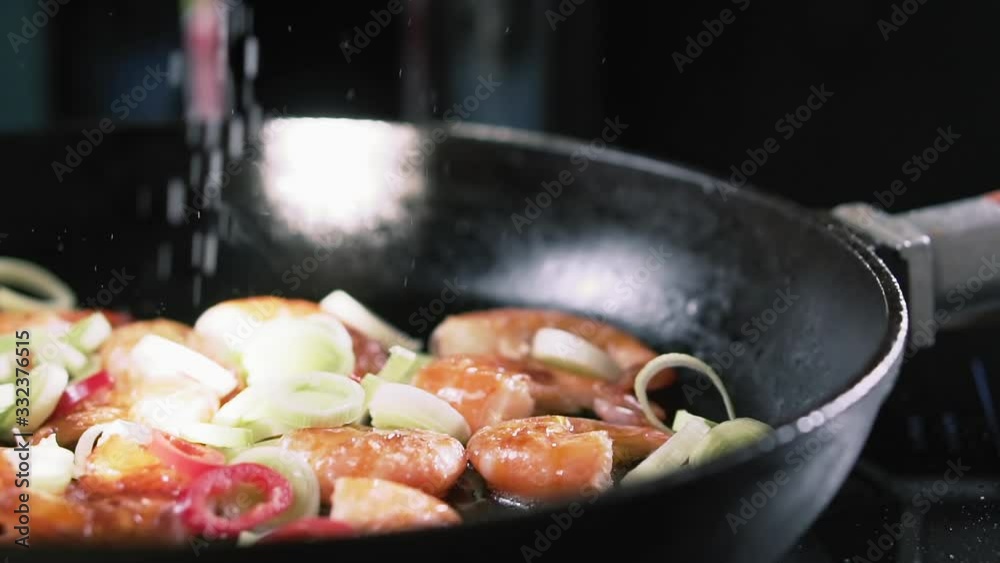 Salt falls in pan with fried shrimps and vegetables, slow motion. Salt falls in pan with fried shrimps and vegetables, slow motion.