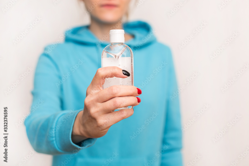 Young Girl in blue hoodie using alcohol antiseptic gel, holds in hands sanitizer to avoid contaminating with dangerous infection Young Girl in blue hoodie using alcohol antiseptic gel, holds in hands sanitizer to avoid contaminating with dangerous infection