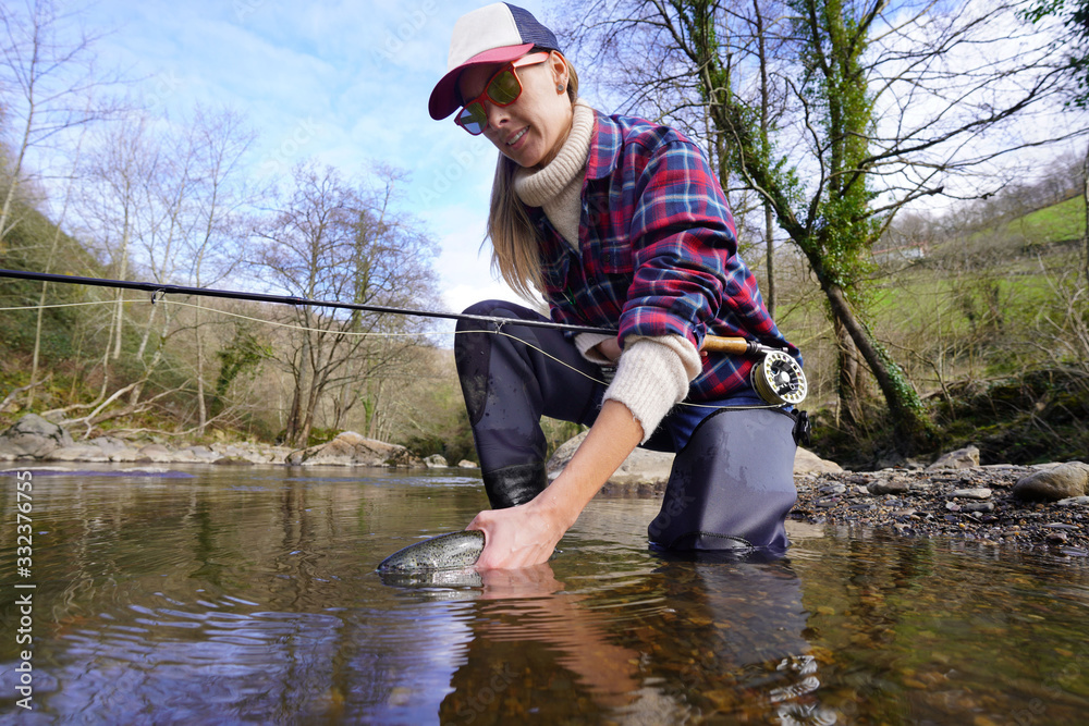 woman catching rainbow trout fly in river woman catching rainbow trout fly in river