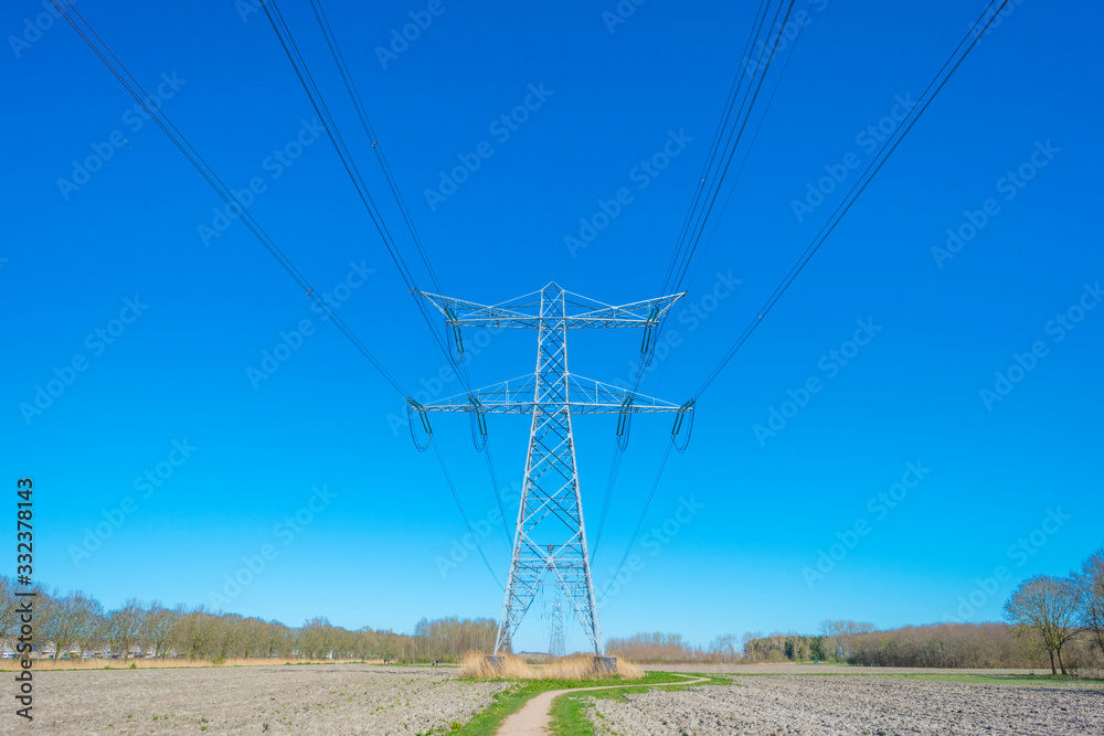 Transmission tower in a blue sky in sunlight in spring
