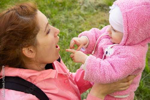 mom sits on the grass in the shade of a blossoming apple tree. plays and hugs his daughters