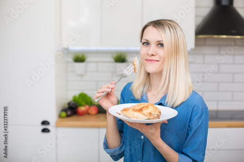 A girl in a blue denim shirt is holding a plate with ready-made chicken breast white meat. Dietary and proper nutrition