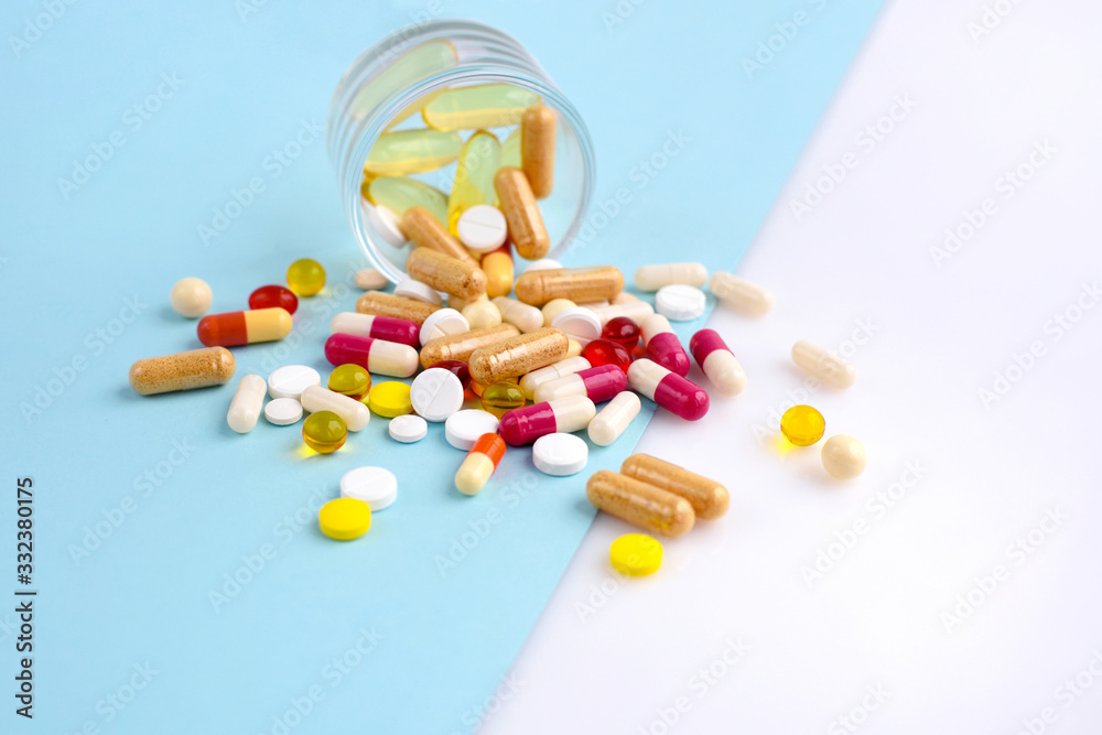 Assorted pharmaceutical medicine pills, tablets and capsules on blue and white background. Space for your text