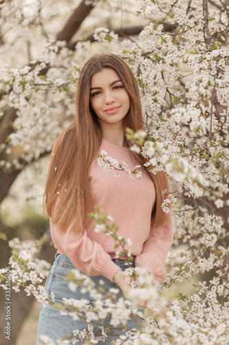 Portrait of pretty young girl in the garden of blossom cherry trees. Spring time © _chupacabra_