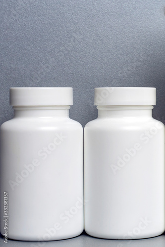two white jars for vitamins and medicines without inscriptions on a gray background.