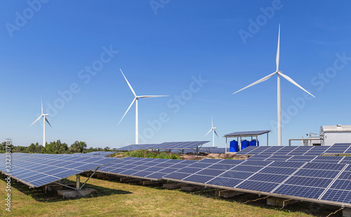 solar cells with wind turbines generating electricity in hybrid power plant systems station on blue sky background alternative renewable energy from nature Ecology concept. 