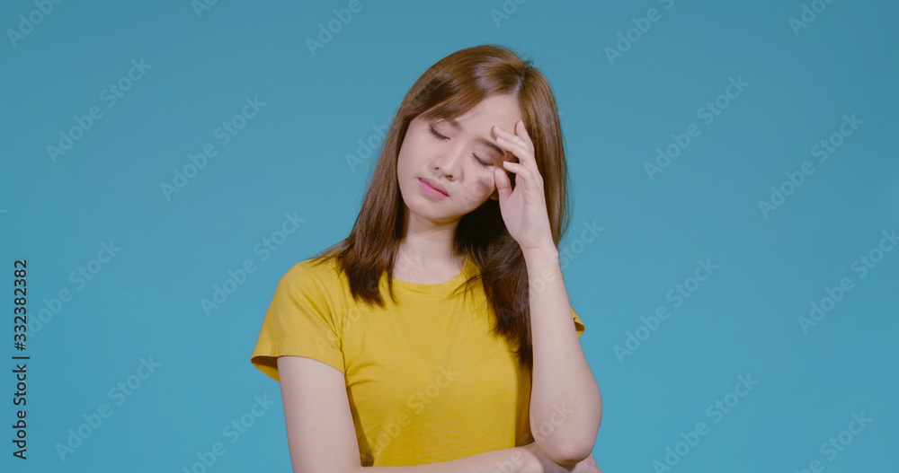 Unhappy young asian woman stressed worried depression healthy her very headache feeling on blue background isolated studio shot. Unhappy young asian woman stressed worried depression healthy her very headache feeling on blue background isolated studio shot.