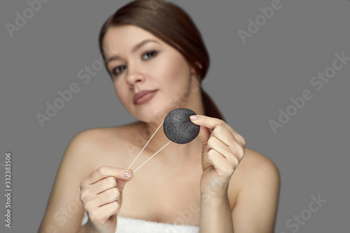 girl make a facial treatment with a black konjac sponge