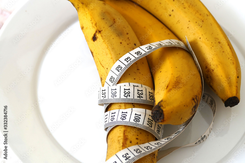 Banana and healthy weight loss, banana and diet, with tape measure on white background, Banana and healthy weight loss, banana and diet, with tape measure on white background,