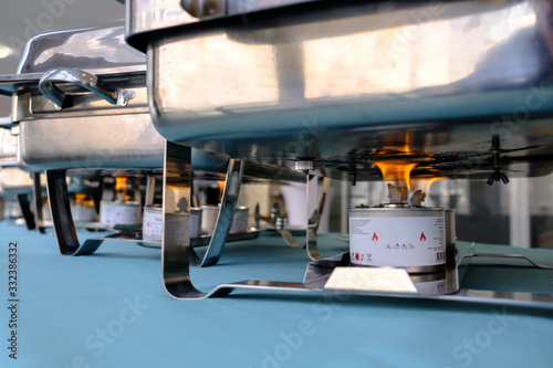 Fotografie Flames from an alcohol burner under a brilliant stainless steel food warmer