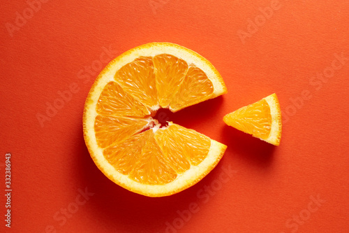 Orange slice symbolizing vitamin c is eating the cut out piece on orange background photo