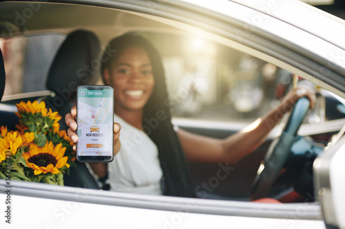 Obraz na płótnie Smiling female driver accepting new request via car sharing application