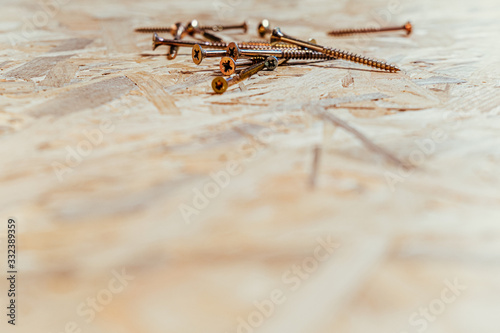 Screws on a wooden table background, screwdriver housework repairmen. © moonphasestudio