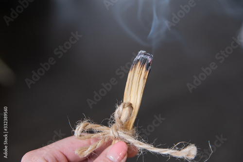 Zbliżenie ręka trzyma palące się drewno. Szamanka używa kadzidło do aromaterapii.  photo
