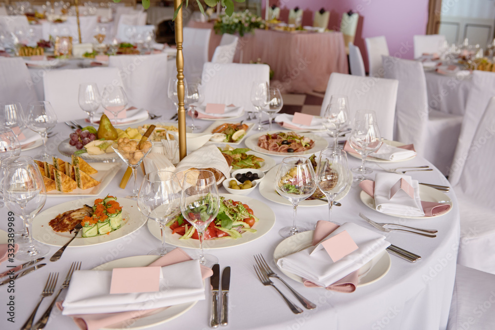 Table setting with blank guest card, white plate with pink napkin and cutlery on table, copy space. Place setting at wedding reception. Table served for wedding banquet in restaurant