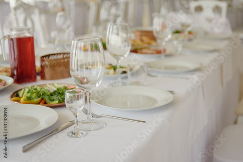 Table setting with wineglasses, plates and cutlery on table, copy space. Place setting at wedding reception. Table served for wedding banquet in restaurant