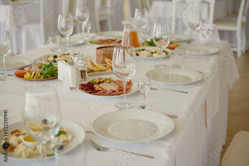 Table setting with wineglasses, plates and cutlery on table, copy space. Place setting at wedding reception. Table served for wedding banquet in restaurant