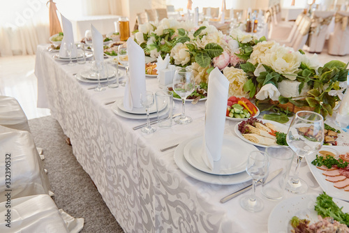 Table set with plates  white serviettes and cutlery on table  copy space. Place setting at wedding reception. Table served for wedding banquet in restaurant