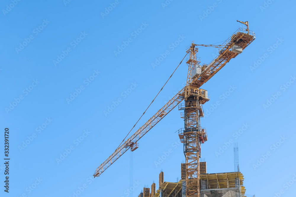 Building under construction, crane on a background of blue sky Building under construction, crane on a background of blue sky