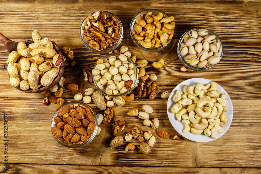 Assortment of nuts on wooden table. Almond, hazelnut, pistachio, peanut, walnut and cashew in small bowls. Top view. Healthy eating concept Assortment of nuts on wooden table. Almond, hazelnut, pistachio, peanut, walnut and cashew in small bowls. Top view. Healthy eating concept