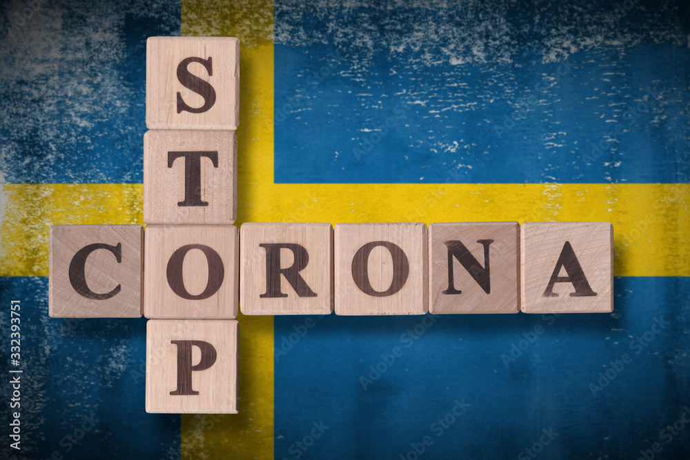 Fototapeta premium Flag of Sweden with wooden cubes spelling STOP CORONA on it. 2019 - 2020 Novel Coronavirus (2019-nCoV) concept art, for an outbreak occurs in Sweden.