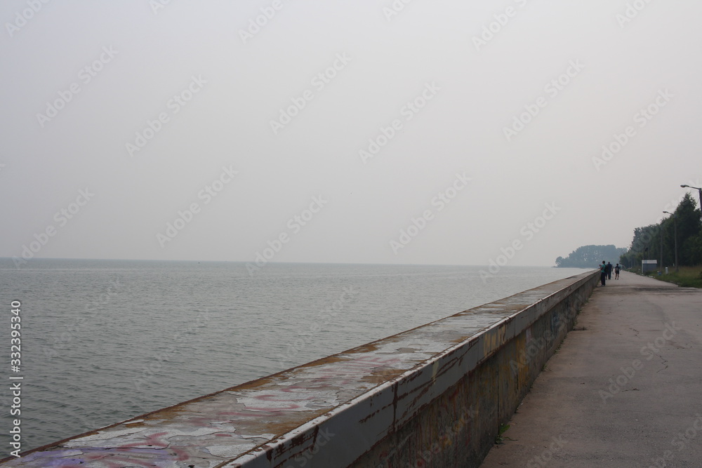 Obraz premium concrete fence on the pier embankment sea separates the water from the shore on the horizon
