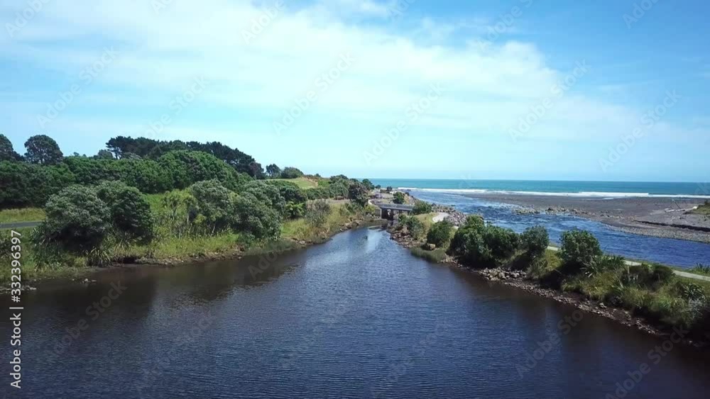 Aerial drone shot, flying over lake towards a bridge into the ocean on a sunny day in New Plymouth, New Zealand Aerial drone shot, flying over lake towards a bridge into the ocean on a sunny day in New Plymouth, New Zealand