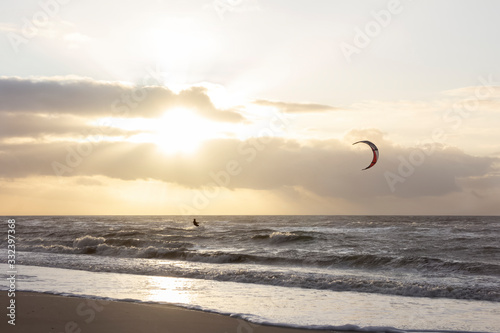 View of the north sea beach on a windy winter day at sunset, people, kitesurfing. Noordwijk, the Netherlands
