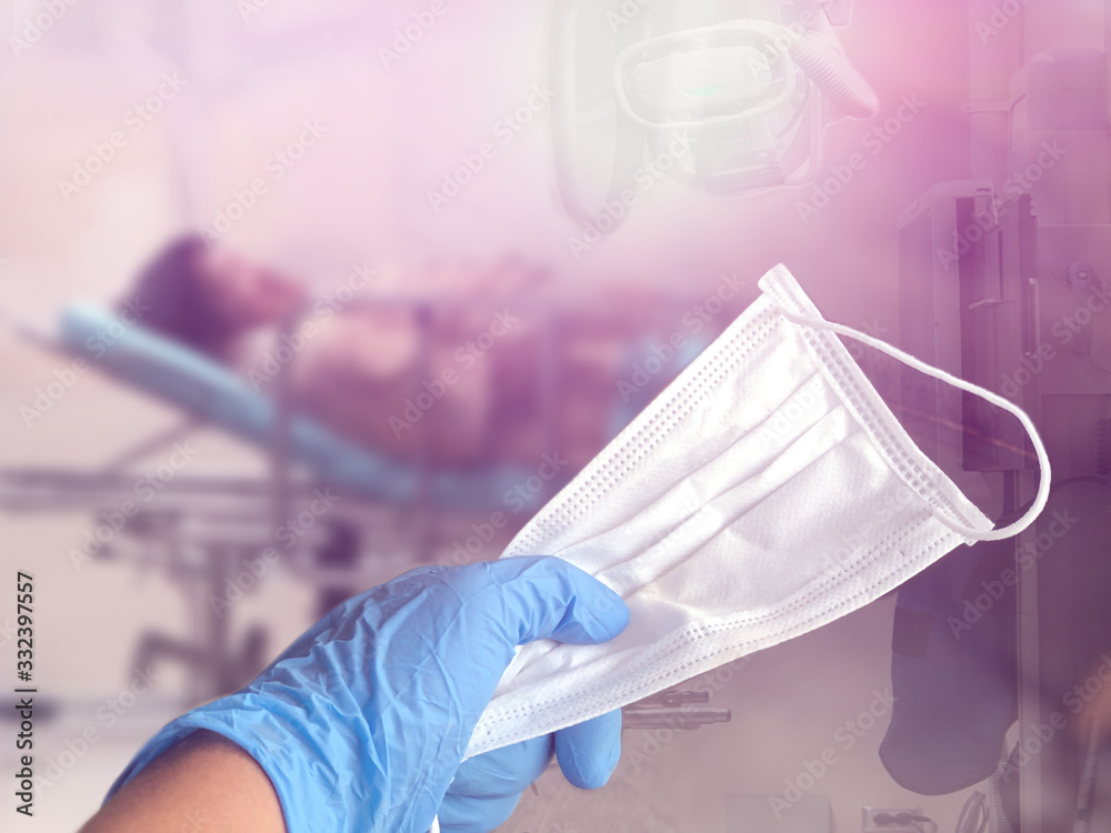 Fototapeta premium Hand holding the hygienic mask,blurred Elderly patients in hospital emergency rooms,with lens flare,selective focus.Prevents coronavirus concept.