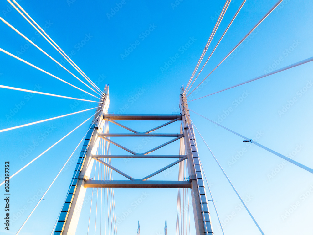 Pylons with steel ropes of the cable-stayed bridge agains clear blue sky. Detail of the multi-span bridge in Saint Petersburg, Russia. Pylons with steel ropes of the cable-stayed bridge agains clear blue sky. Detail of the multi-span bridge in Saint Petersburg, Russia.