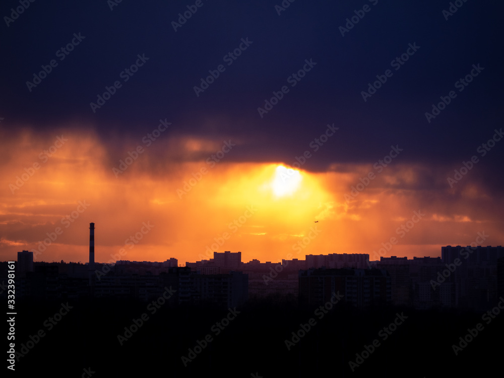Colorful cloudy epic sky on sunset over the panoramic silhouette of the Moscow city skyline with far silhouette of the commercial jet