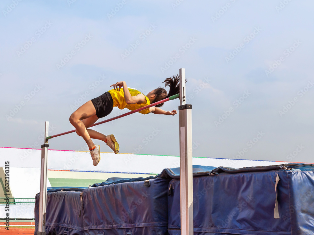 female athlete in action high jump over bar in track and field Stock