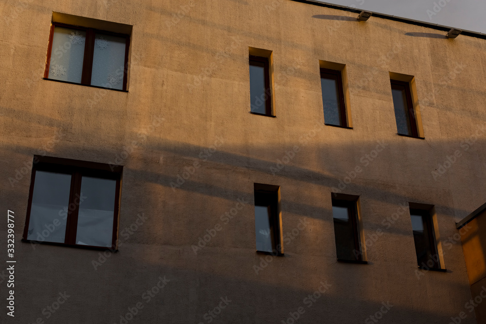 Fototapeta premium Wall of a building with windows. The building is lit by the setting sun.