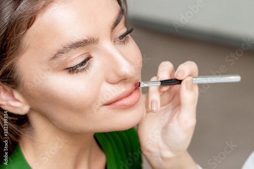 Makeup artist applies lipstick.
