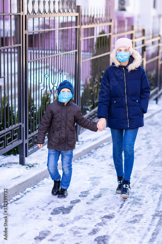 Young woman with little boy wearing medical face masks to protect themselve from pollution, germs and coronavirus on the street during quarantine. Corona virus, covid -19, pandemic protection concept. photo
