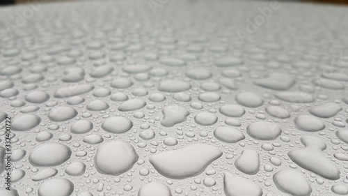 Getrennte Regentropfen auf einer silbernen Oberfläche (Autodach) closeup