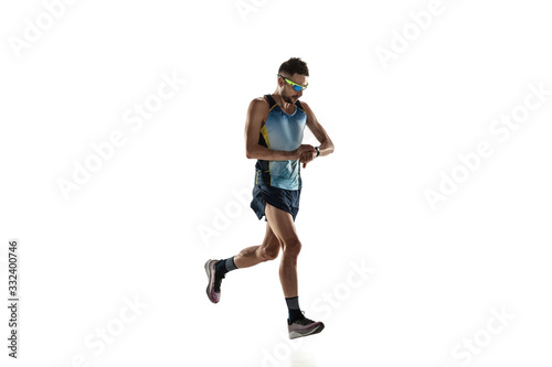 Triathlon male athlete running isolated on white studio background. Caucasian fit jogger, triathlete training wearing sports equipment. Concept of healthy lifestyle, sport, action, motion. Time check.