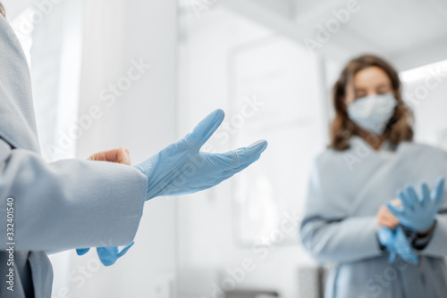 Woman in medical mask wearing gloves while going outside, protecting from the virus during an epidemic. Concept of coronavirus pandemic and protection against viral infections