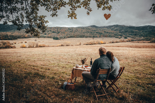 Couple have lunch together on meadow in autumn nature