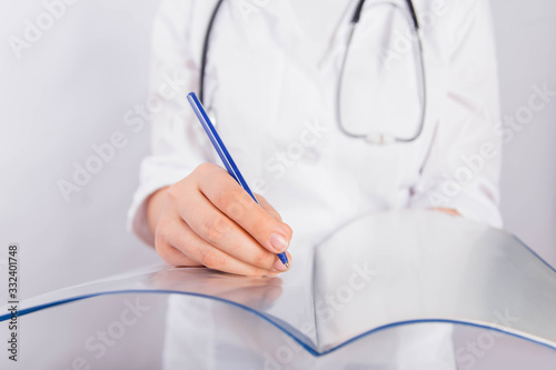 Doctor's hands in a white coat hold a folder and fill out a medical document close-up isolated on a white background.