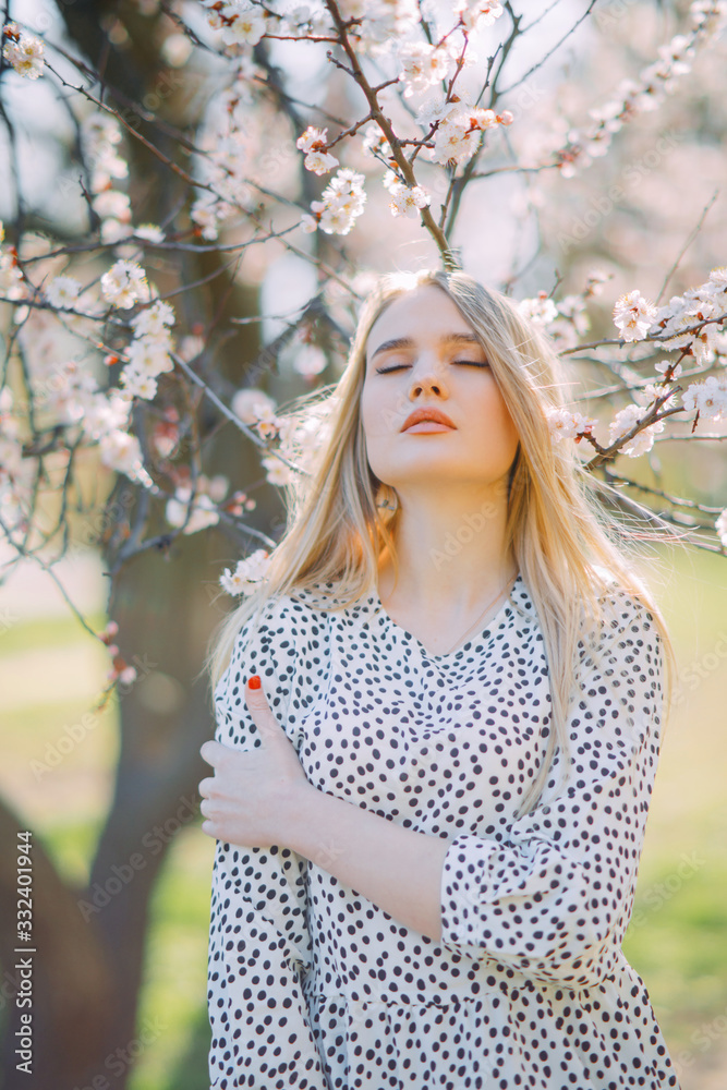 A young woman stands among blossoming apricot trees. A young woman stands among blossoming apricot trees.