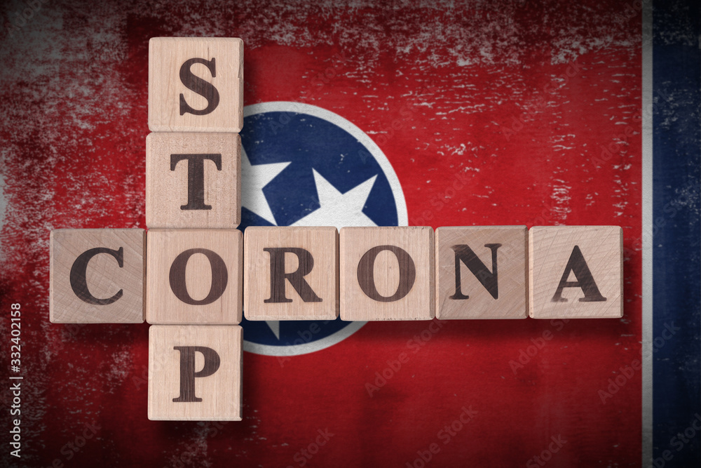 Obraz premium Flag of the state of Tennessee with wooden cubes spelling STOP CORONA on it. 2019 - 2020 Novel Coronavirus (2019-nCoV) concept art, for an outbreak occurs in Tennessee, US.