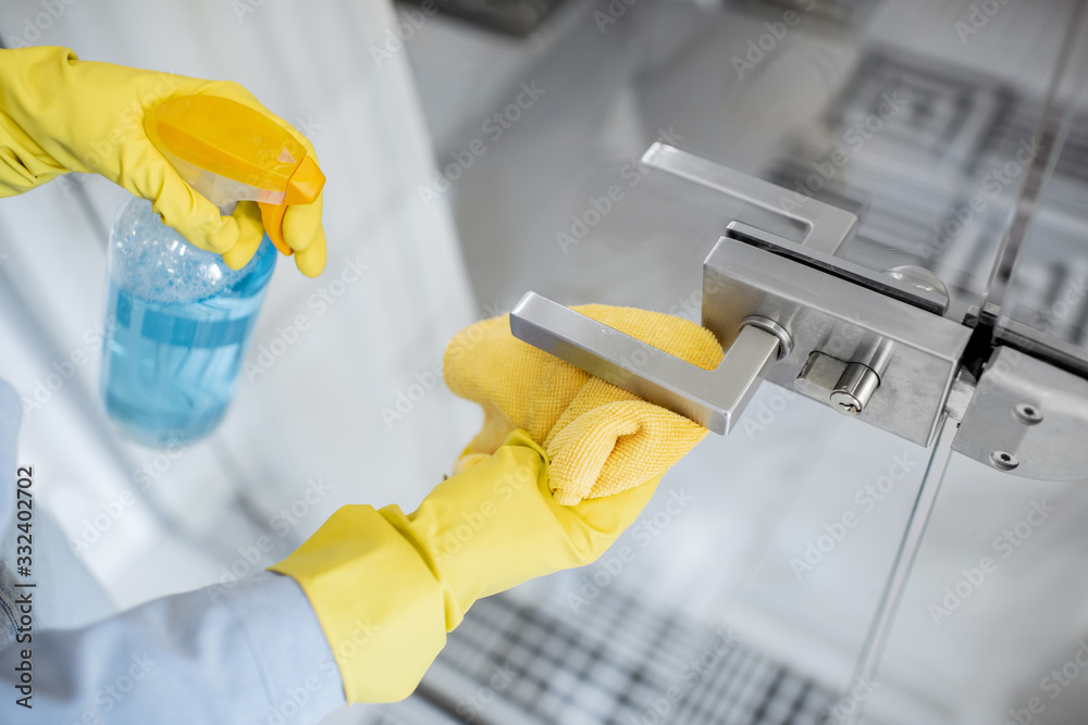 Woman in protective gloves disinfecting door handle while cleaning at home, close-up view on hands - obrazy, fototapety, plakaty 
