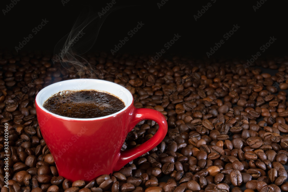 coffee in a small red cup with steam on the background of coffee beans coffee in a small red cup with steam on the background of coffee beans