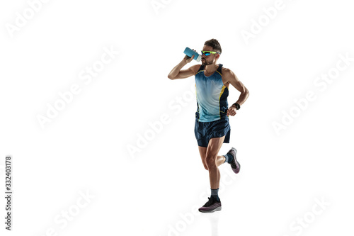 Triathlon male athlete running isolated on white studio background. Caucasian fit jogger, triathlete training wearing sports equipment. Concept of healthy lifestyle, sport, action, motion. Drinks