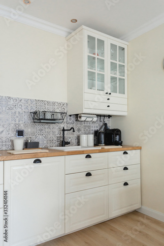 Fototapeta Naklejka Na Ścianę i Meble -  Cozy, bright Scandinavian-style kitchen. White, gray, black. Dishwashing sink, faucet, metal dishwasher, tile with patterns.