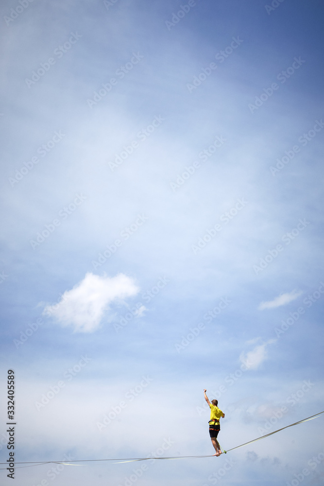 tightrope walker on a mountain with blue sky and clouds tightrope walker on a mountain with blue sky and clouds