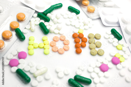 The concept of pills for treatment. Multi-colored pills in blisters on a white isolate. The word hope laid out from different pills. Hope for cure, hope for medicine. A serving of pills for today. Da